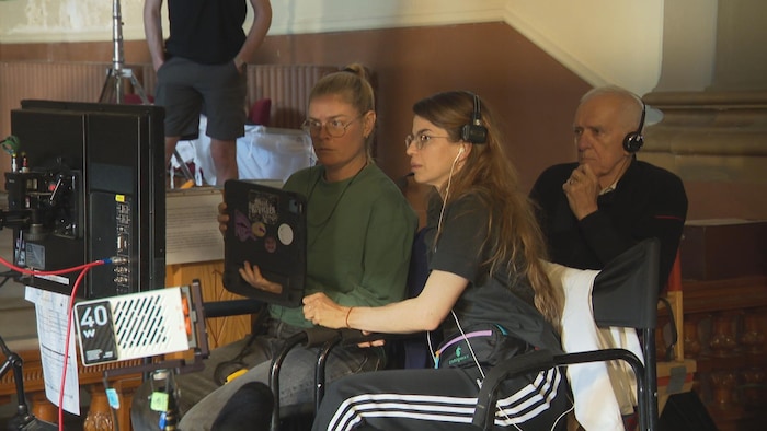 Trois personnes sont derrière une caméra.