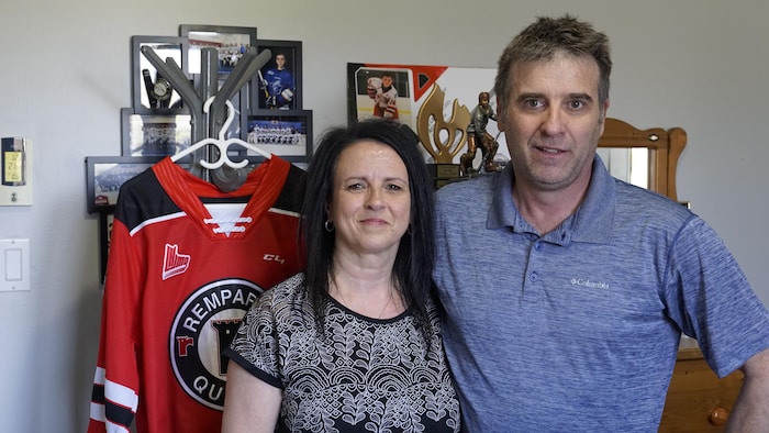 Une femme et un homme devant des souvenirs liés au hockey.