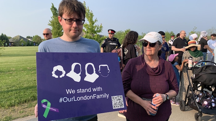 Un garçon qui tient une pancarte sur laquelle est écrit «Our London family»