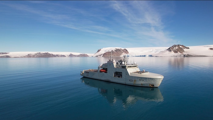 Le navire de la marine royale devant un glacier.