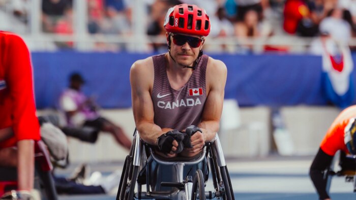Un athlète en fauteuil roulant regarde la caméra. 