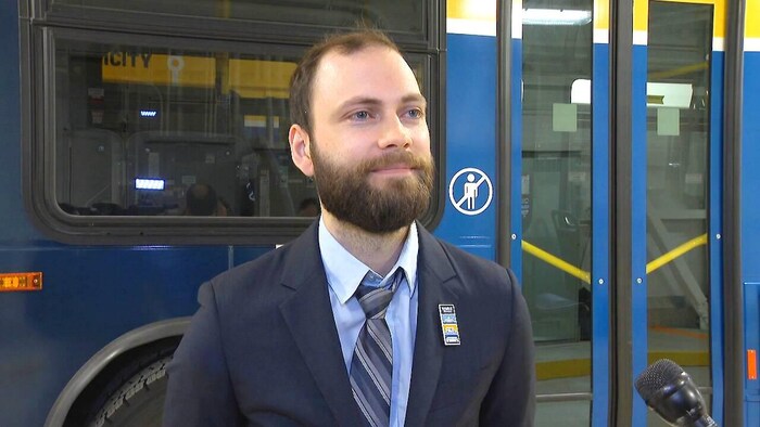 Anthony Edmonds fièrement debout devant un autobus.