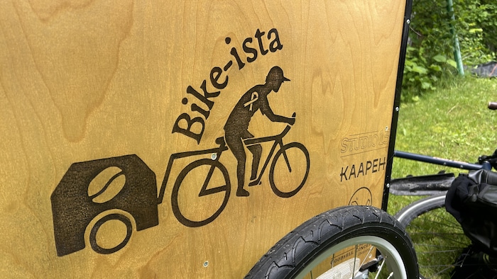 un cycliste qui tire une petite remorque marquée d'un icône de café.
