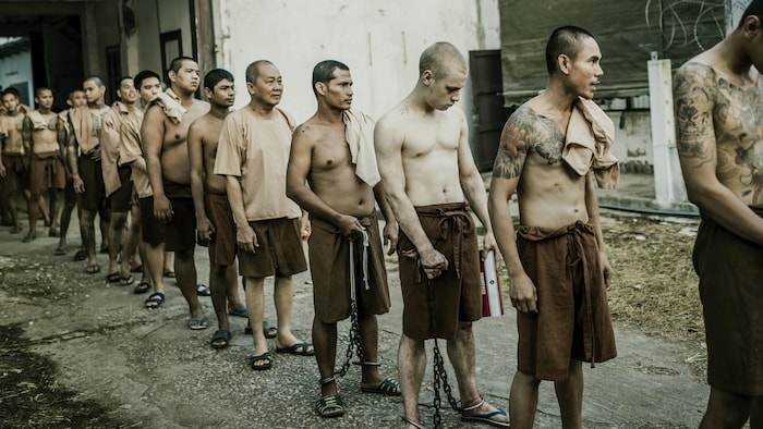 Le comédien Antoine Olivier Pilon est dans une file, dans une scène du film « Suspect numéro un ». Tous les hommes sont costumés en prisonniers thaïlandais.
