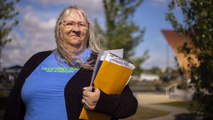 Antoinette Gravel-Ouellette se tient debout à l'extérieur avec des documents dans les mains.