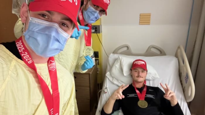 Anton Amundrud célèbre avec ses coéquipiers, couché sur le lit d'hôpital.
