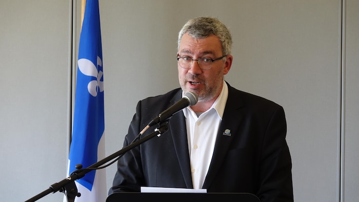Le maire des Îles-de-la-Madeleine derrière le lutrin lors de l'annonce.