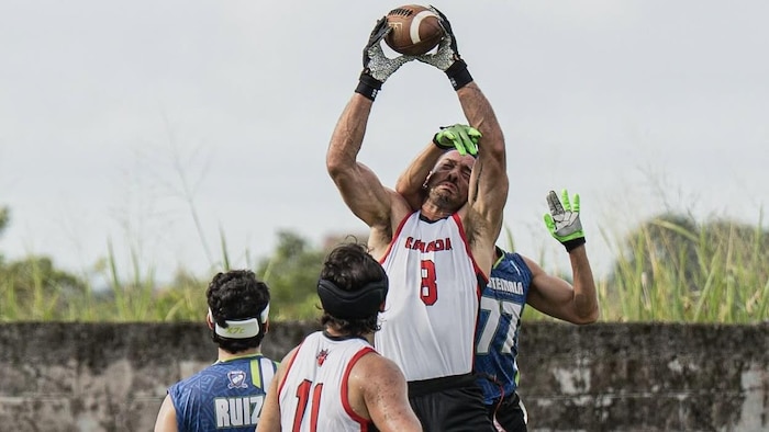 He catches a ball while jumping, eyes closed, while an opposing player tries to prevent him.