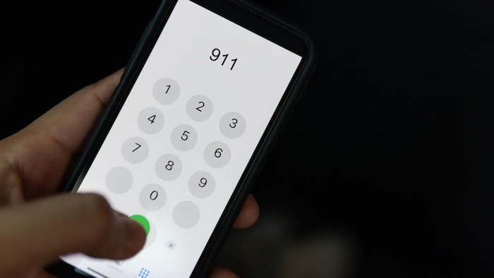 Une personne compose le 911 sur un téléphone.