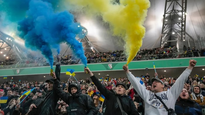 المتفرجون يدعمون الفريق الأوكراني خلال مباراة ودية لكرة القدم الخيرية بين ليغيا وارسزاوا ودينامو كييف في ملعب الجيش البولندي في وارسو ، بولندا ، 12 أبريل 2022 (Czarek Sokolowski / Associated Press)