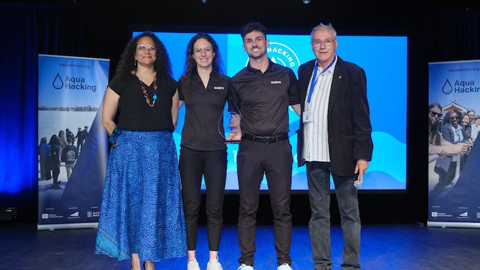 Les gagnants du défi AquaHacking reçoivent leur prix sur scène en compagnie de deux dignitaires.