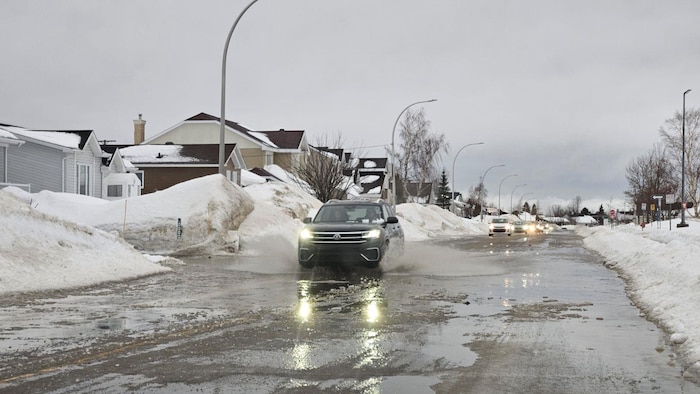 Un véhicule circule dans une rue inondée par la fonte des neiges, à Sept-Îles.