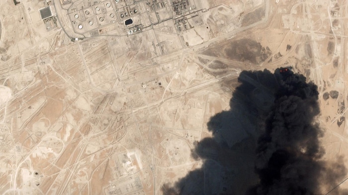 Un épais nuage de fumée noire au-dessus d'un vaste terrain sablonneux.
