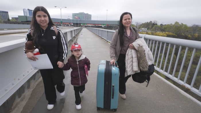 Une mère et ses deux filles traversent un pont à pied.