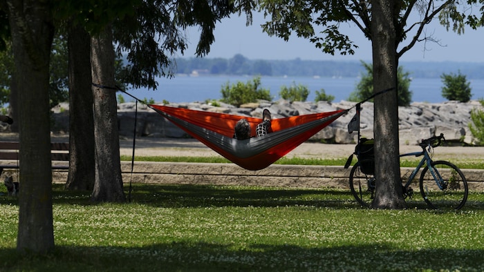 Une personne relaxe dans un hamac au bord de l'eau.