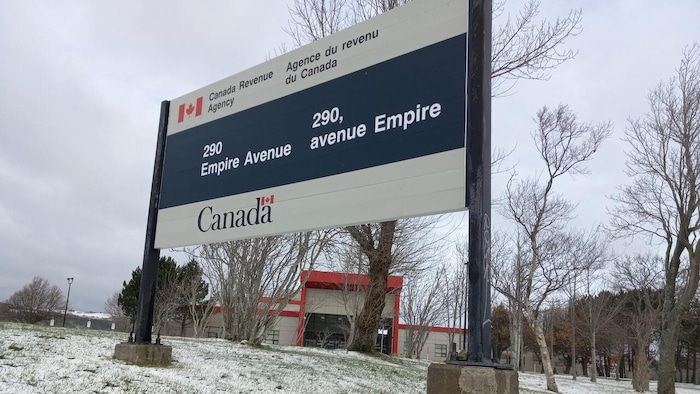 L'enseigne de l'Agence du revenu du Canada posée sur des blocs de béton sur la pelouse couverte d'une fine couche de neige.