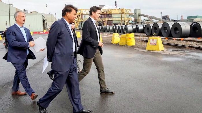 Justin Trudeau, alors premier ministre du Canada (à droite), marche avec Sean Donnelly, président et chef de la direction d’ArcelorMittal Dofasco (à gauche), et Lakshmi Mittal, président directeur, le 13 octobre 2022.