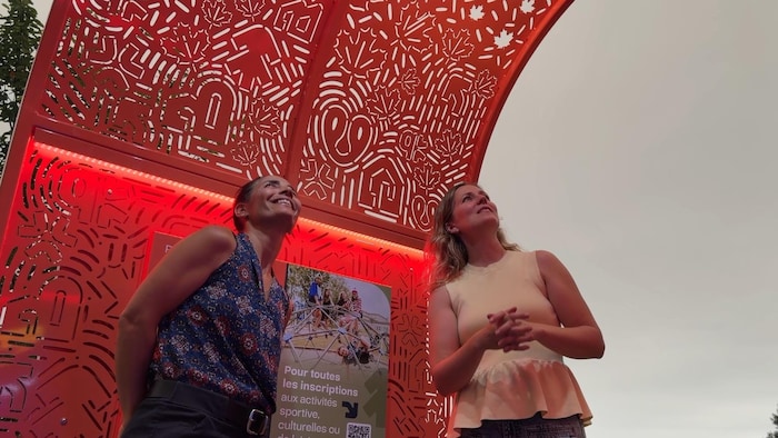 Deux personnes regardent les motifs sur la structure.