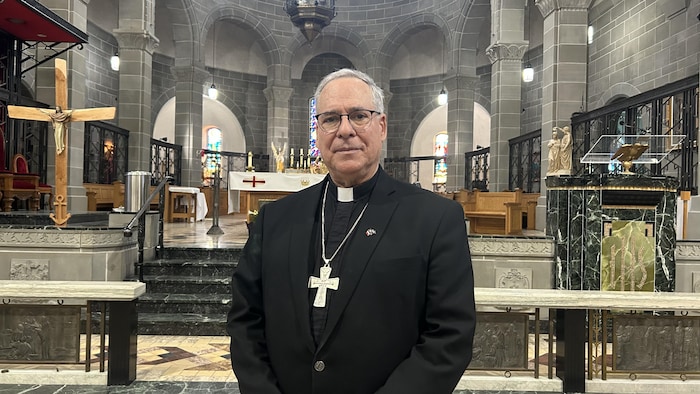 Mgr Guy Desrochers devant l'autel de la cathédrale de Moncton. 