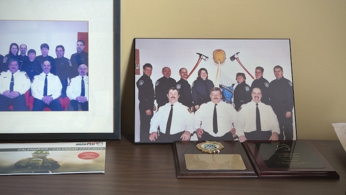 Des photos et plaques commémoratives du service incendie de Longue-Rive sont exposées sur un meuble.
