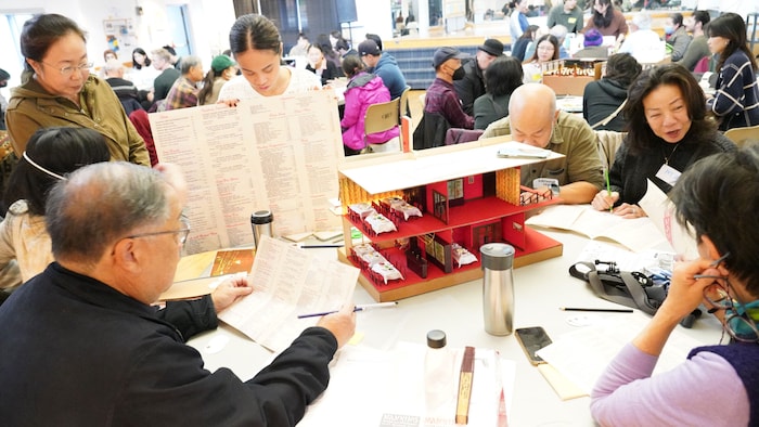 Une table réunissant des membres de la communauté sino-canadienne devant une maquette.