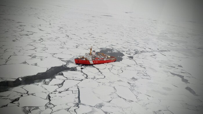vue aérienne d'un bateau naviguant dans une mer de glace.