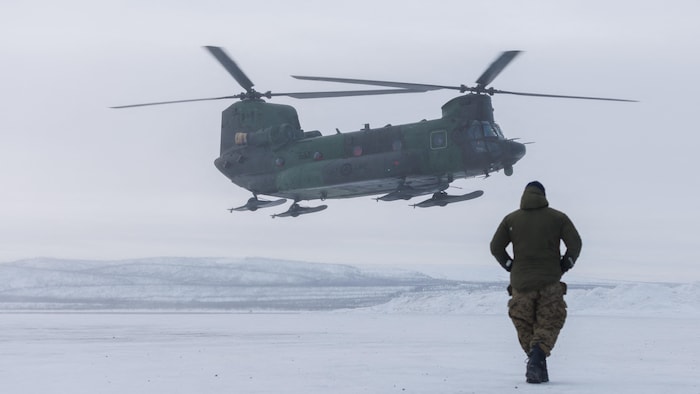 Un homme marche de dos vers un hélicoptère qui s'apprête à se poser au sol durant l'opération militaire Nanook, dans le nord des Territoires du Nord-Ouest, le 1er mars 2025.