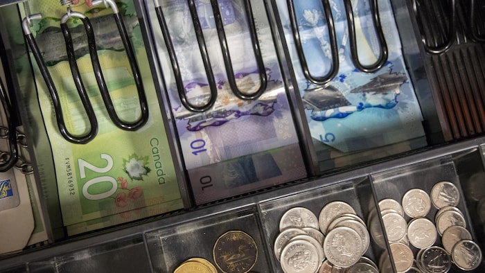 Vue de l'intérieur d'une caisse enregistreuse, remplie de billets et de pièces de monnaie.