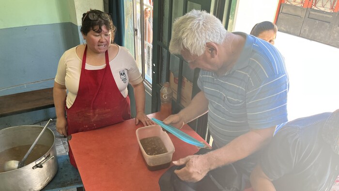 Un homme referme un contenant de plastique dans lequel de la soupe a été versée.