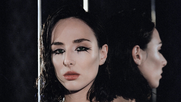 Portrait de la chanteuse et de son reflet sur un miroir derrière elle.