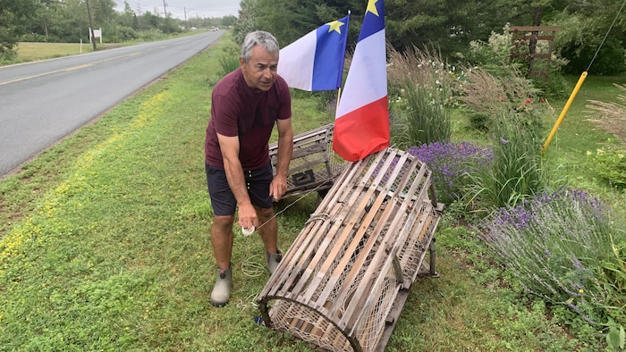 Un homme dehors, près de casiers à homards.