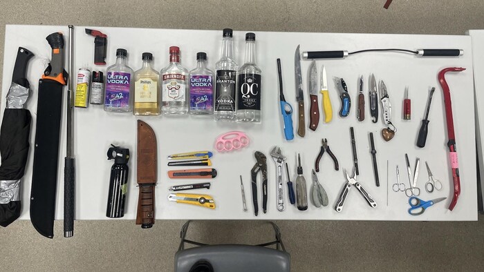 Des armes blanches et des bouteilles d'alcool sont sur une table.