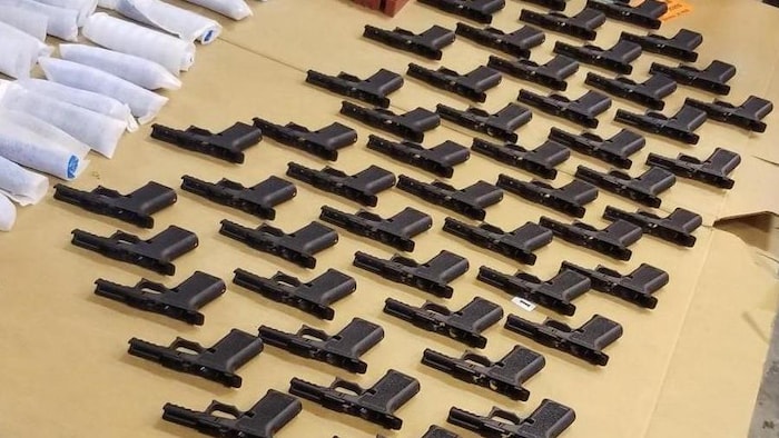 Des pièces d'arme à feu sont alignées sur une table. 