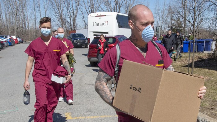 Des hommes masqués portant des uniformes roses transportent du matériel.