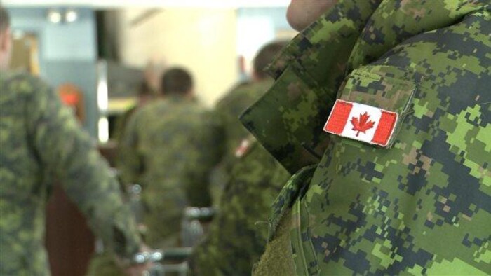 Gros plan sur des militaires canadiens dont on voit l'uniforme, sur lequel se trouve un drapeau canadien.