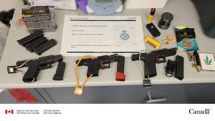 Des armes à feu, des munitions et des chargeurs sont déposés sur une table.