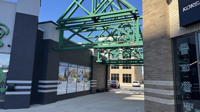 Une allée entre deux commerces, derrière lesquels se trouvent un stationnement. 