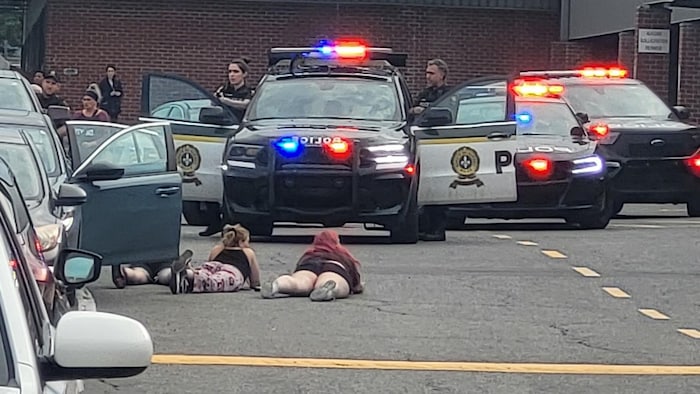 Des femmes couchées devant des voitures de police.