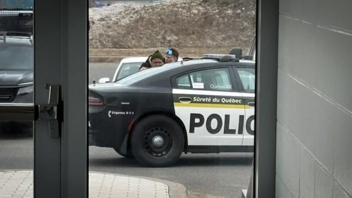 Il est placé en état d'arrestation près d'un véhicule de patrouille de la Sûreté du Québec.