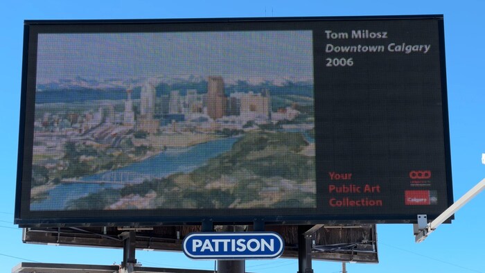 Sur un panneau publicitaire électrique est diffusée la peinture de Tom Milosz intitulée « Dowtown Calgary ».