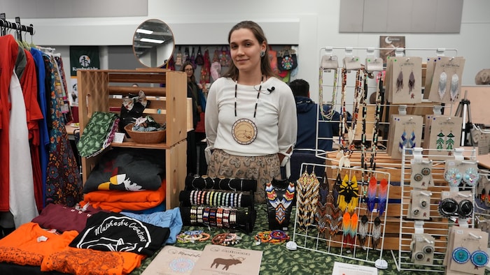 Raphëlle Langevin se tient debout derrière une table remplie d'articles d'artisanat. 