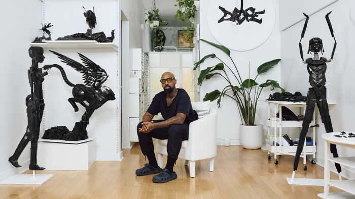 L’artiste Ekow Nimako dans son studio entouré d'une dizaine de sculptures en lego noir. 