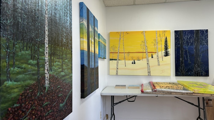 Des tableaux accrochés au mur et déposés sur une table.