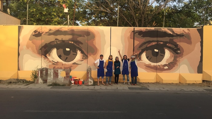 Des personnes devant une murale représentant deux yeux de femme.
