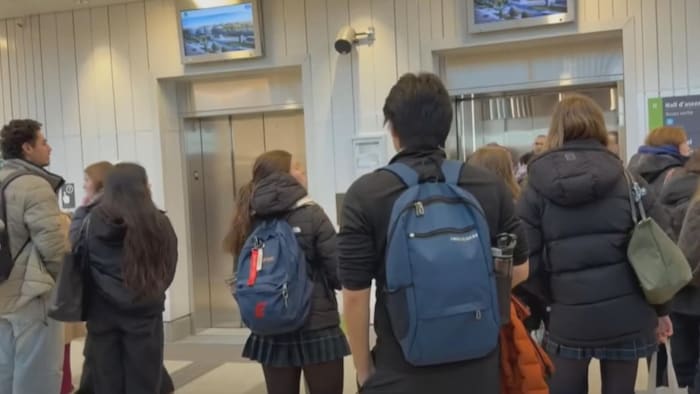 Des gens attendent devant un ascenseur.