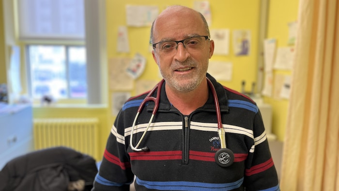 Assaad Taktak debout dans une salle, un stéthoscope accroché à son cou.