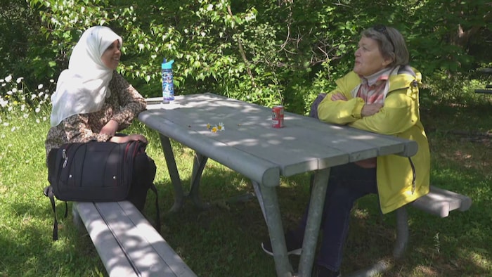 Assia Kassid et Colette Tremblay discutent assises sur une table à pique-nique.