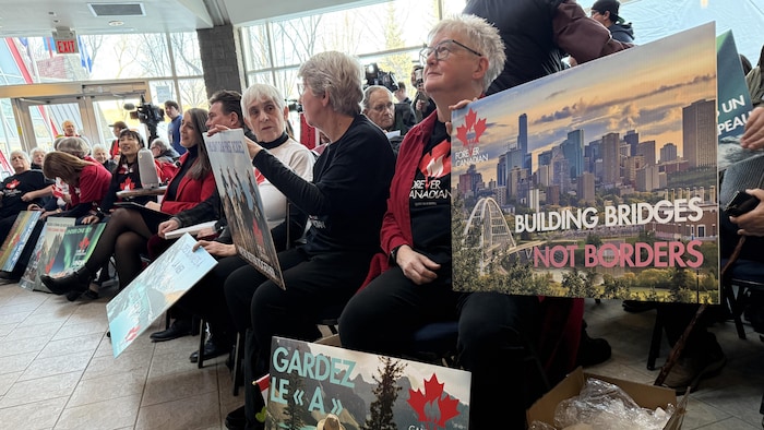 Des femmes brandissent des pancartes en soutien au mouvement Canadiens pour toujours.