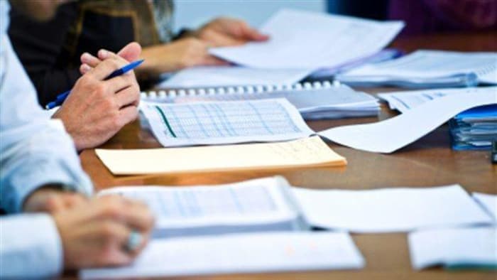 Des mains de personnes et des documents sur une table.