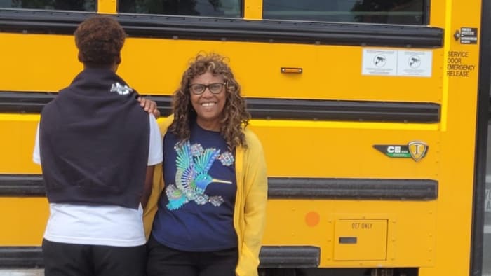 Astérie Ndikumana avec son neveu devant l'autobus scolaire.
